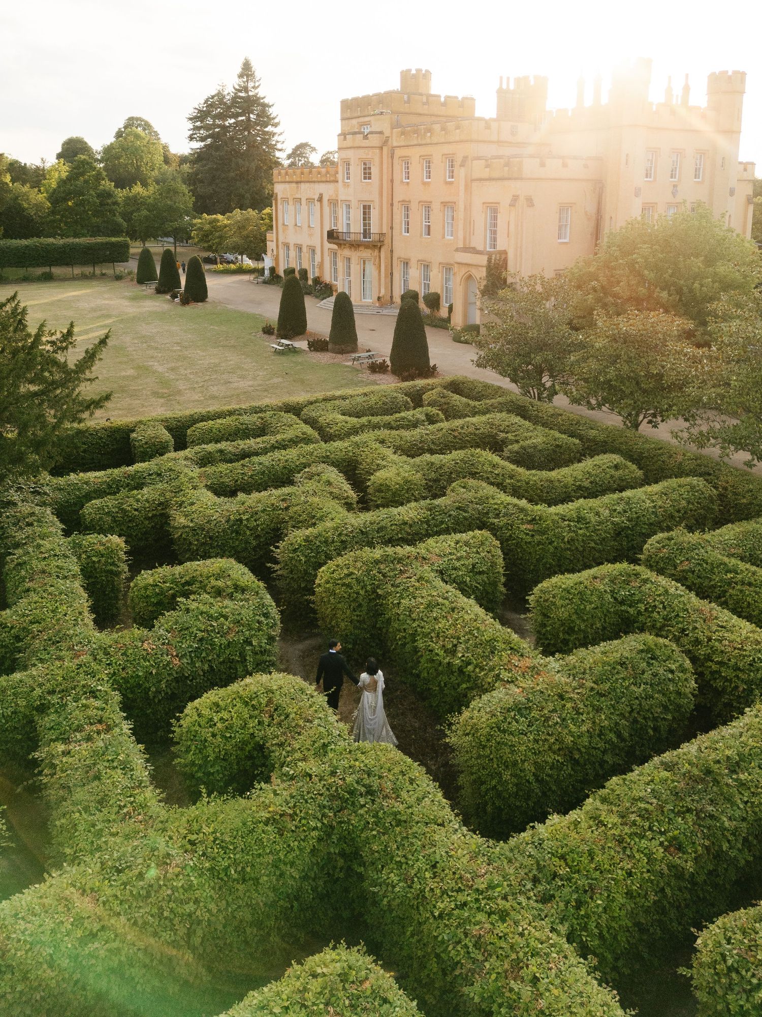 Aerial shot of South Asian bride and groom walking in the labyrinth at Ditton Manor