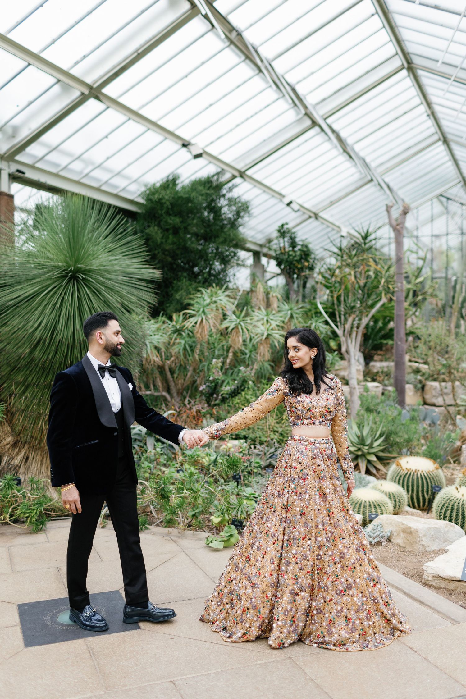 Fashion-forward wedding portrait of a just married Hindu couple holding hands inside Princess of Wales Conservatory at Kew Gardens