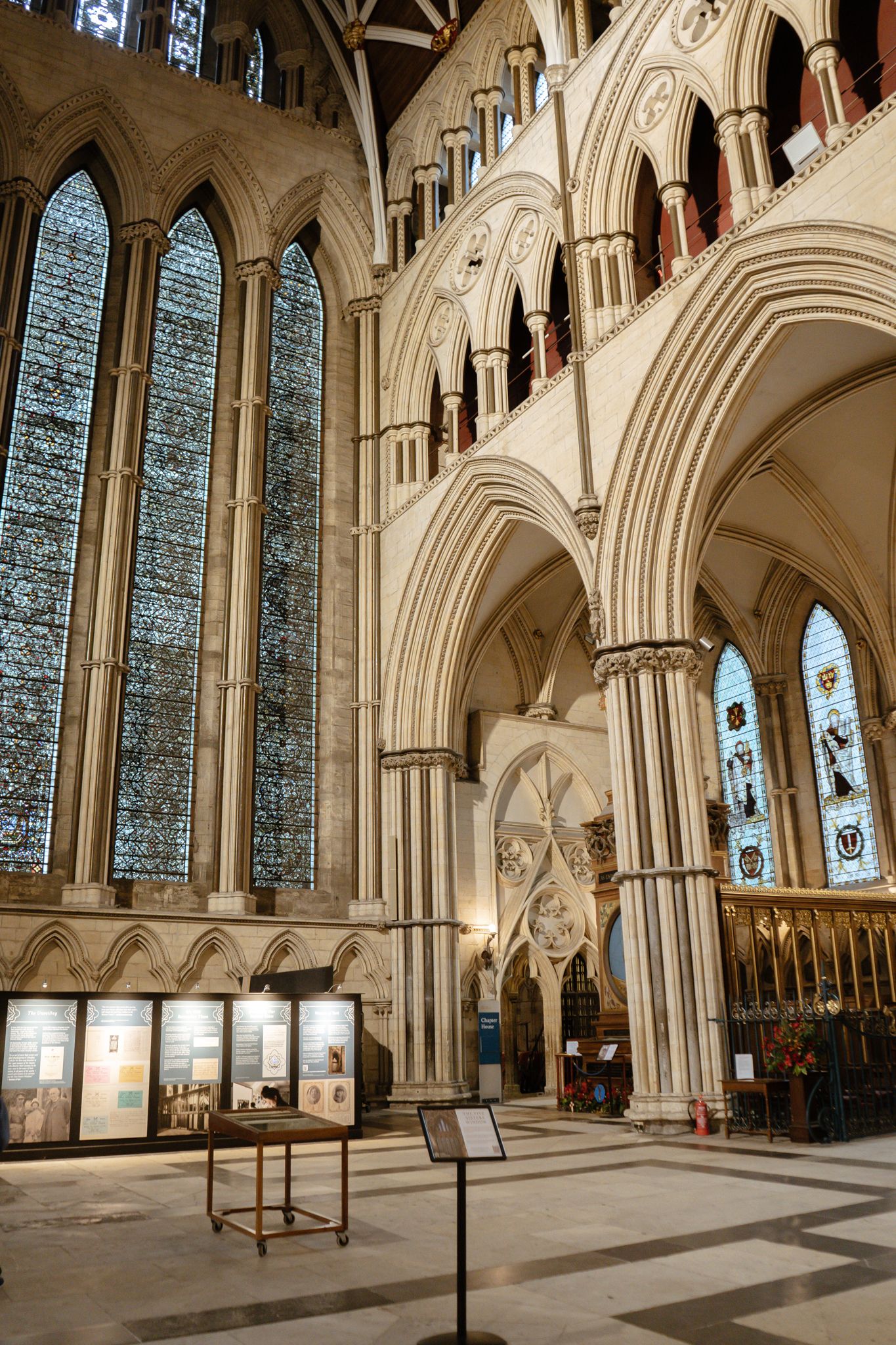 Magnificent Gothic cathedral interior featuring tall stained glass windows, pointed arches, and ornate stone columns.