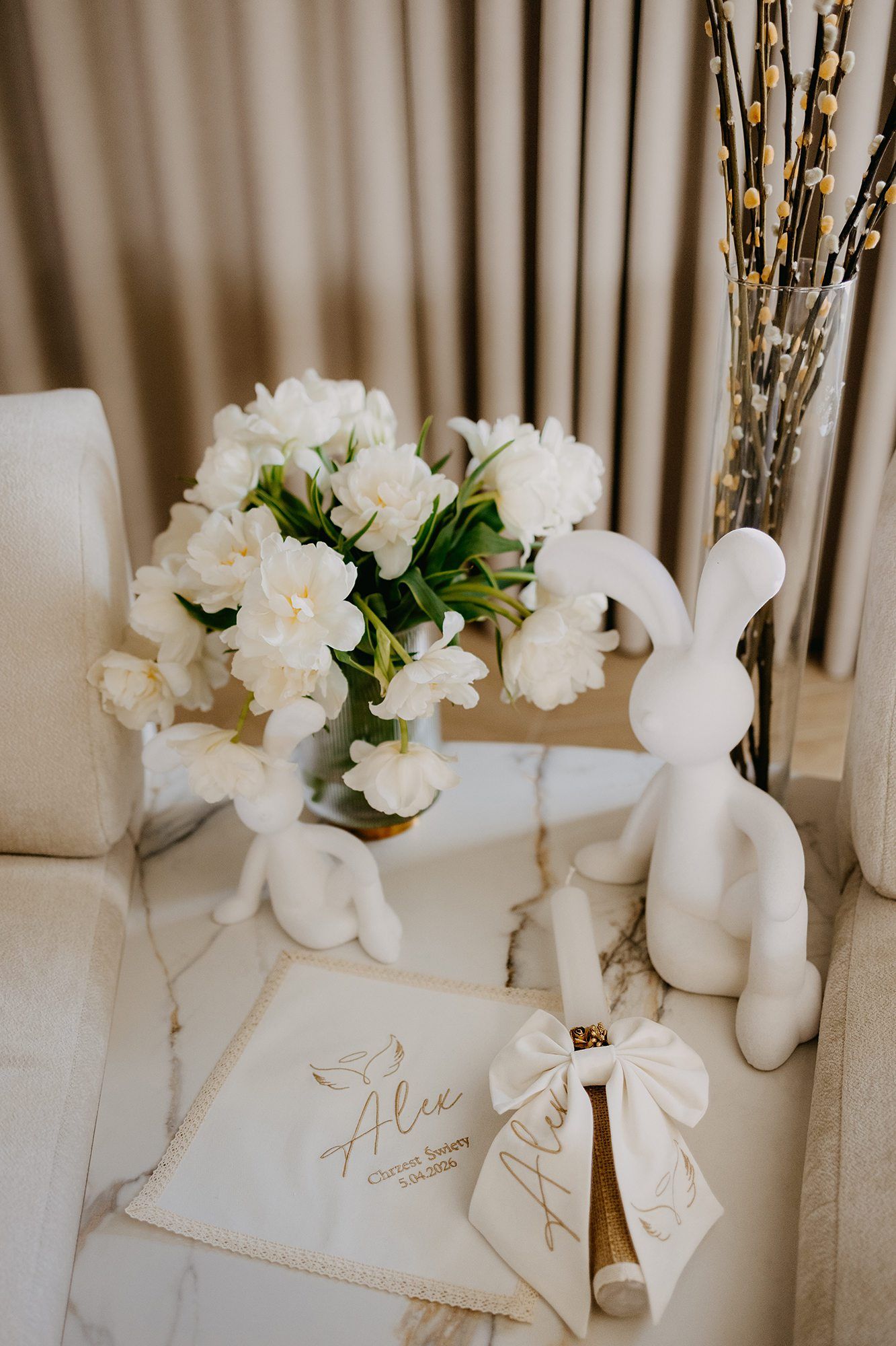 An elegant christening display with white flowers, bunny figurines, and personalized keepsakes.
