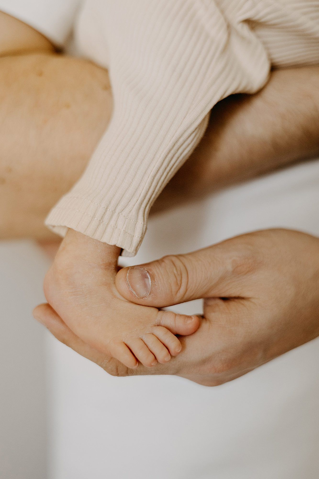 Parent gently holding tiny baby foot in hands.