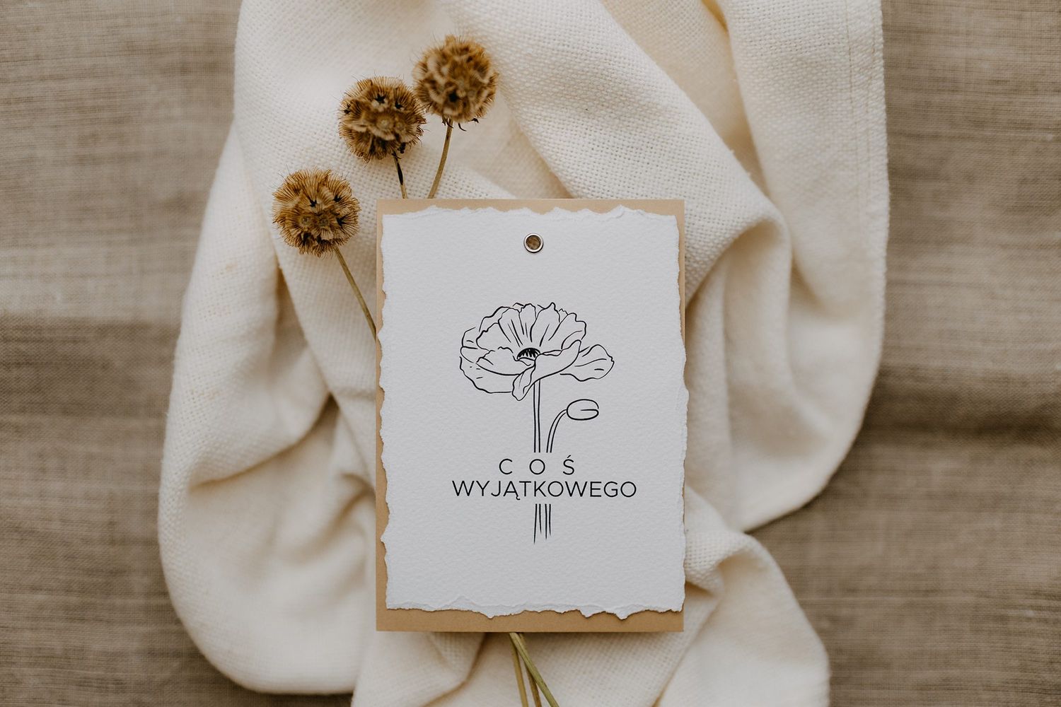 Handmade paper gift tag with botanical flower illustration and Cos Wyjatkowego text on linen fabric.