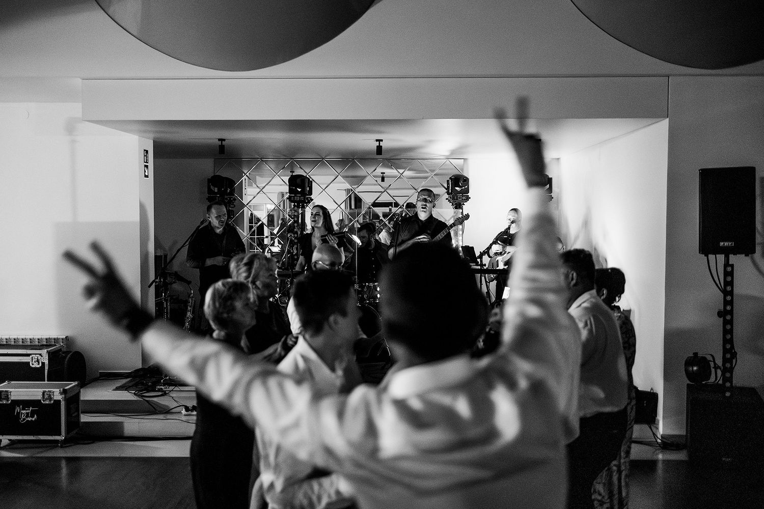 Guests dancing and celebrating at a lively wedding reception with a live band performing on stage.