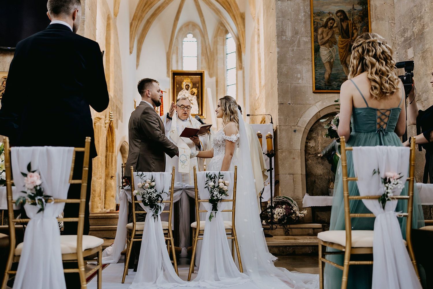 Bride and groom exchange vows at a beautifully decorated church altar during wedding ceremony.