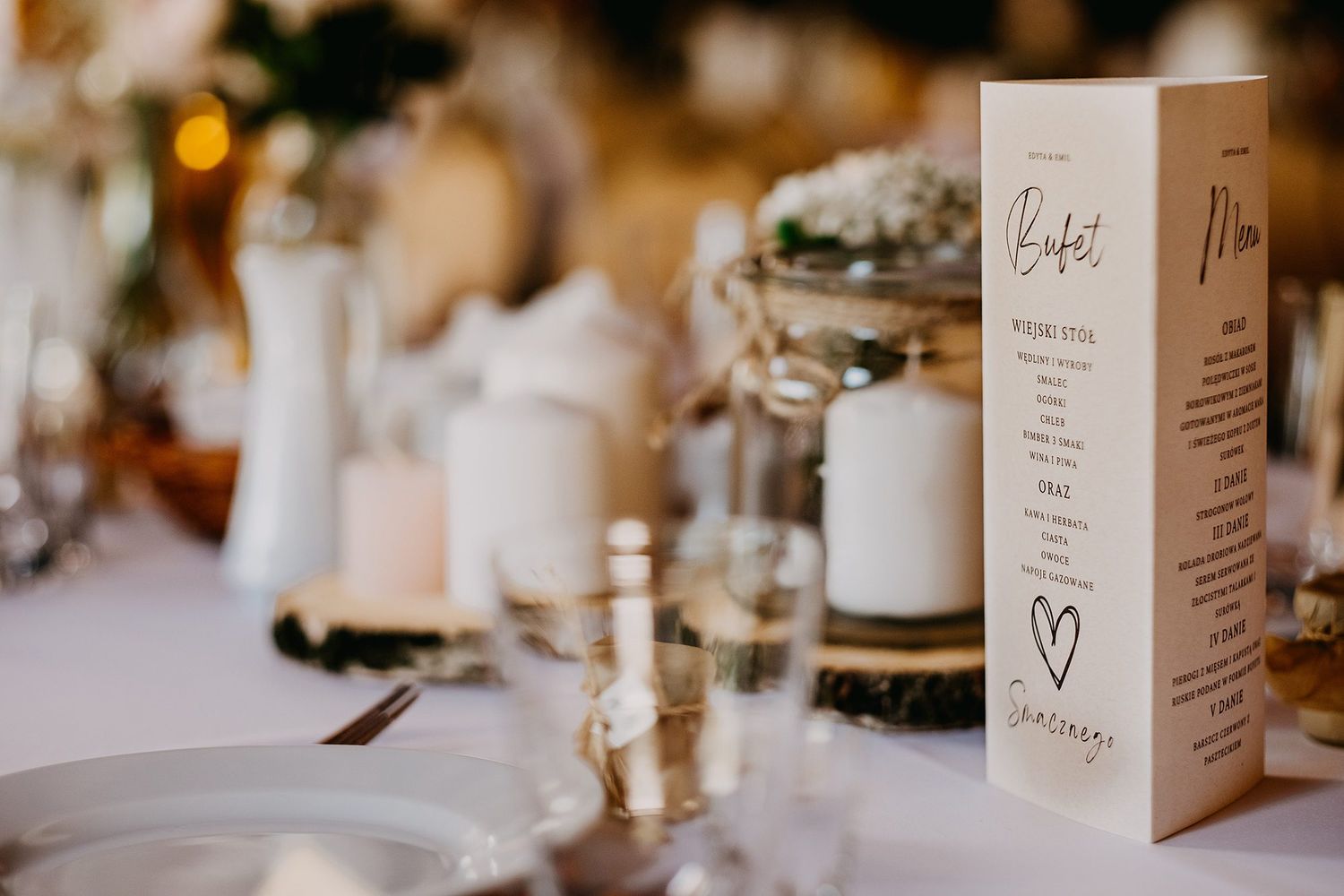 Elegant wedding reception table setting with a menu card, candles, and floral centerpieces.