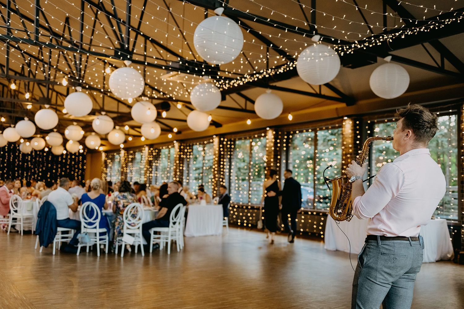 Elegant wedding reception hall decorated with white lanterns and string lights.
