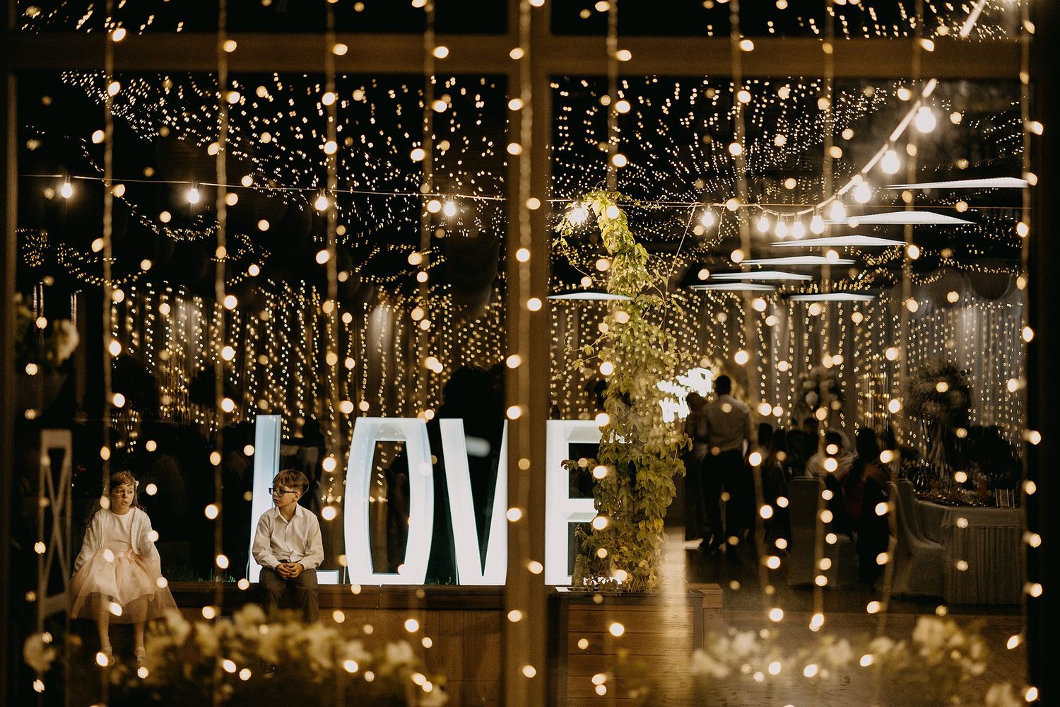 Romantic wedding venue decorated with thousands of warm fairy lights and large illuminated LOVE letters.
