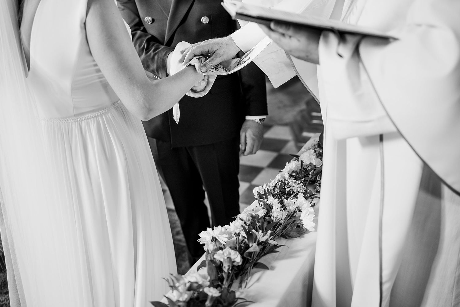 Black and white photo of couple exchanging rings during wedding ceremony at the altar.
