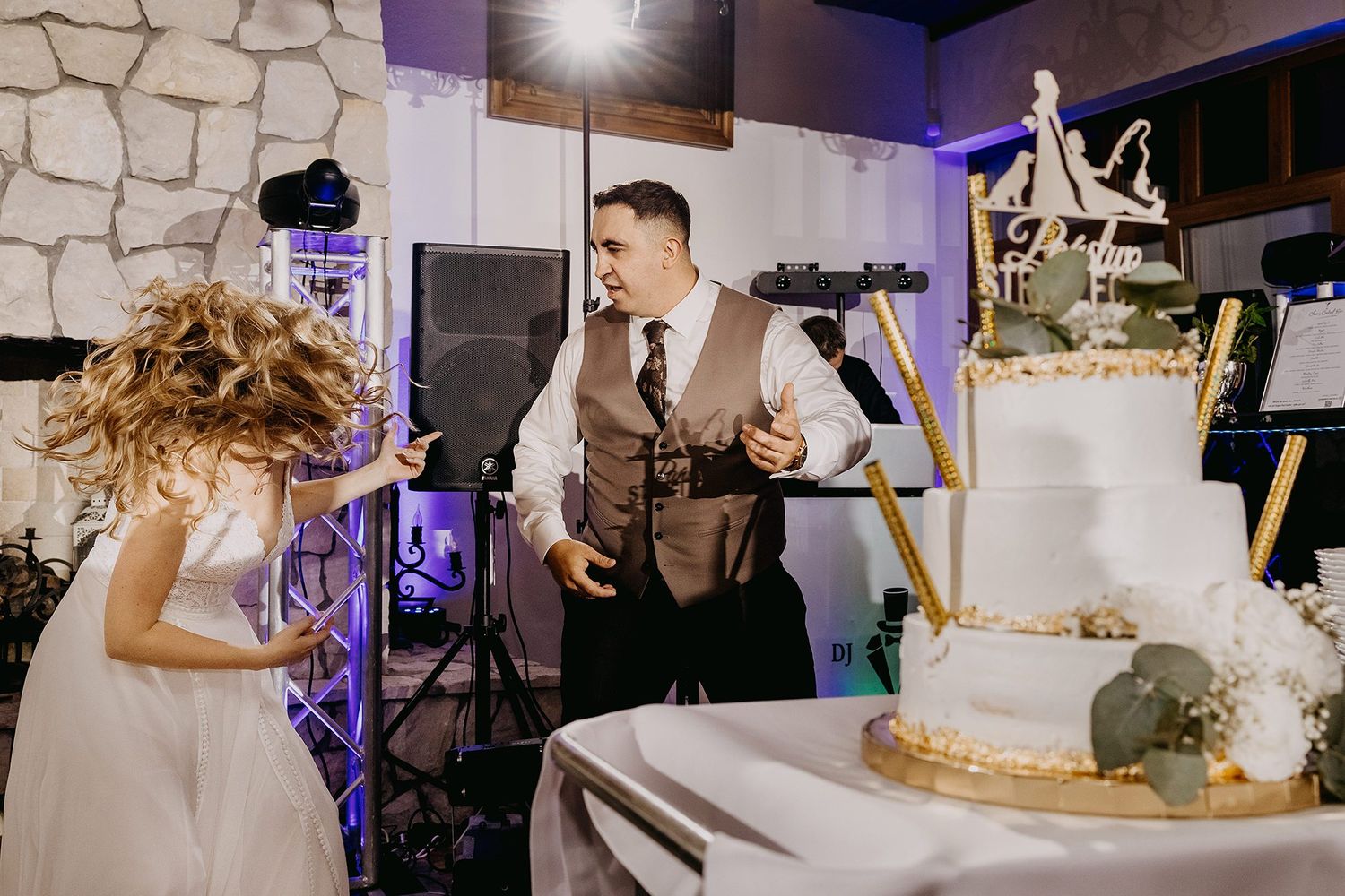 Groom and bride preparing to cut their elegant white multi-tiered wedding cake at the reception.