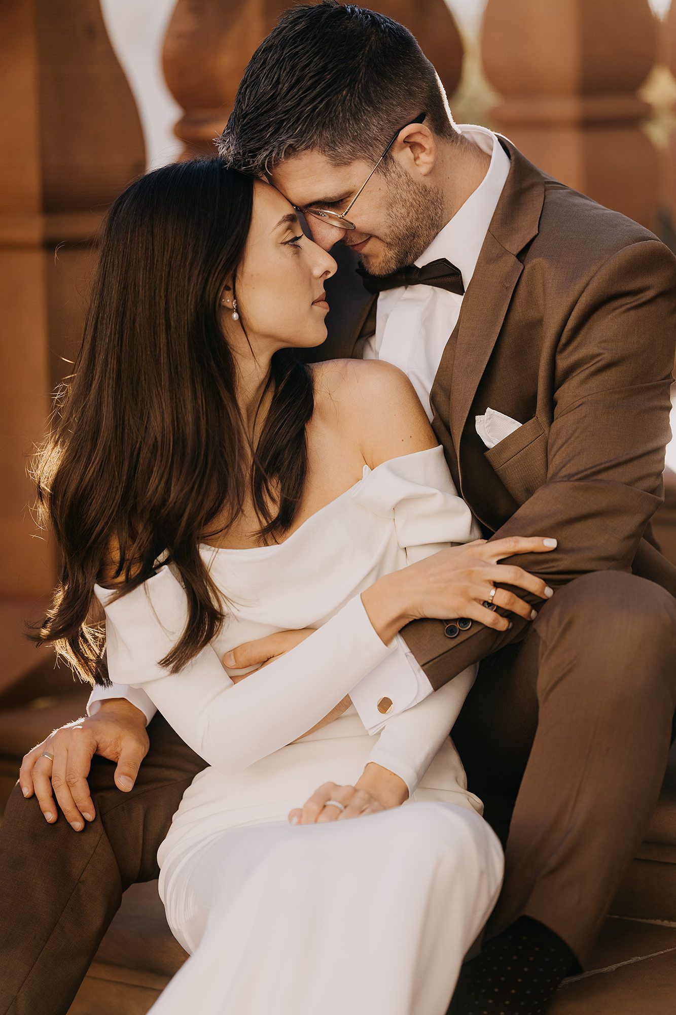 Bride and groom sharing an intimate almost-kiss in warm golden light.