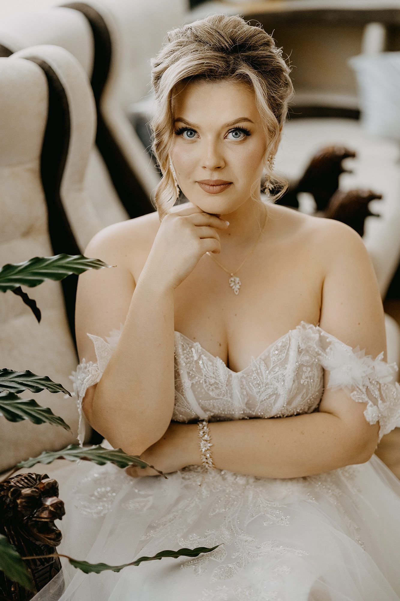 Beautiful bride in an off-shoulder lace wedding gown posing elegantly with a thoughtful expression.