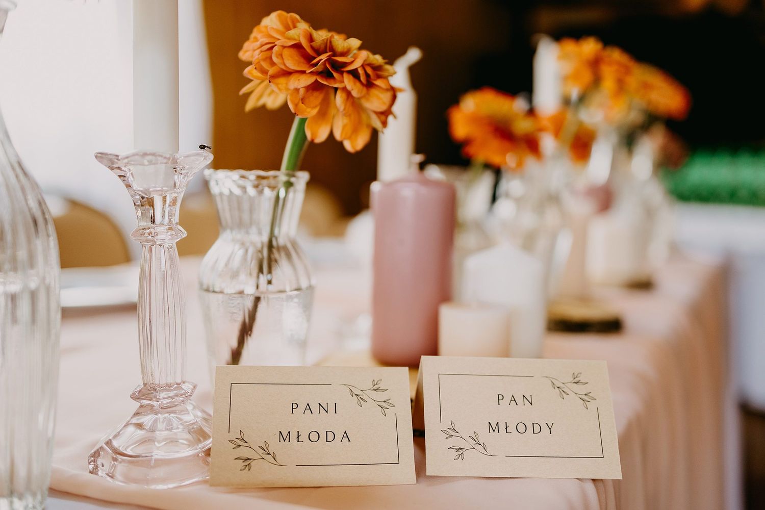 Elegant wedding table place cards reading Pani Mloda and Pan Mlody with orange floral decor.