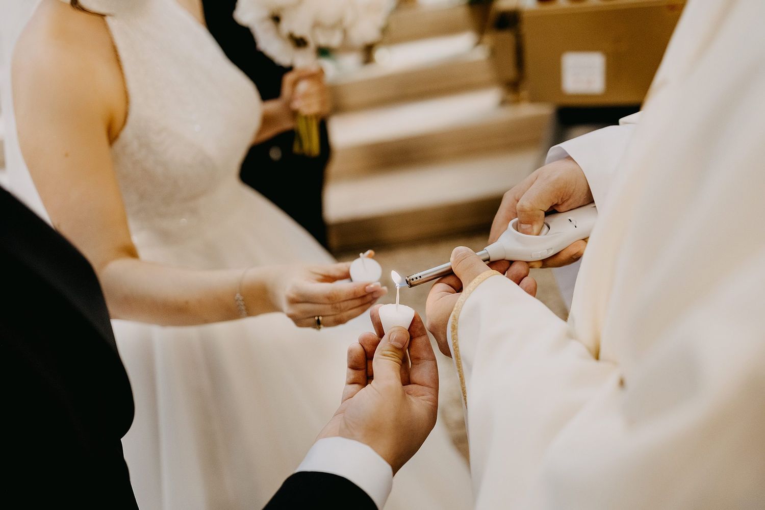 Close-up of wedding ring exchange ceremony with hands holding rings on white pillow.