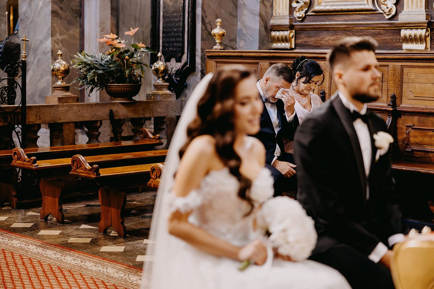 Bride and groom sit at the altar during their elegant church wedding ceremony.