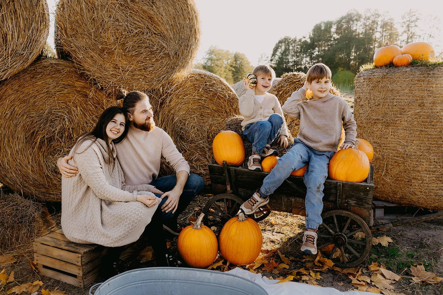Family of five posing with pumpkins and hay bales at an autumn pumpkin patch.