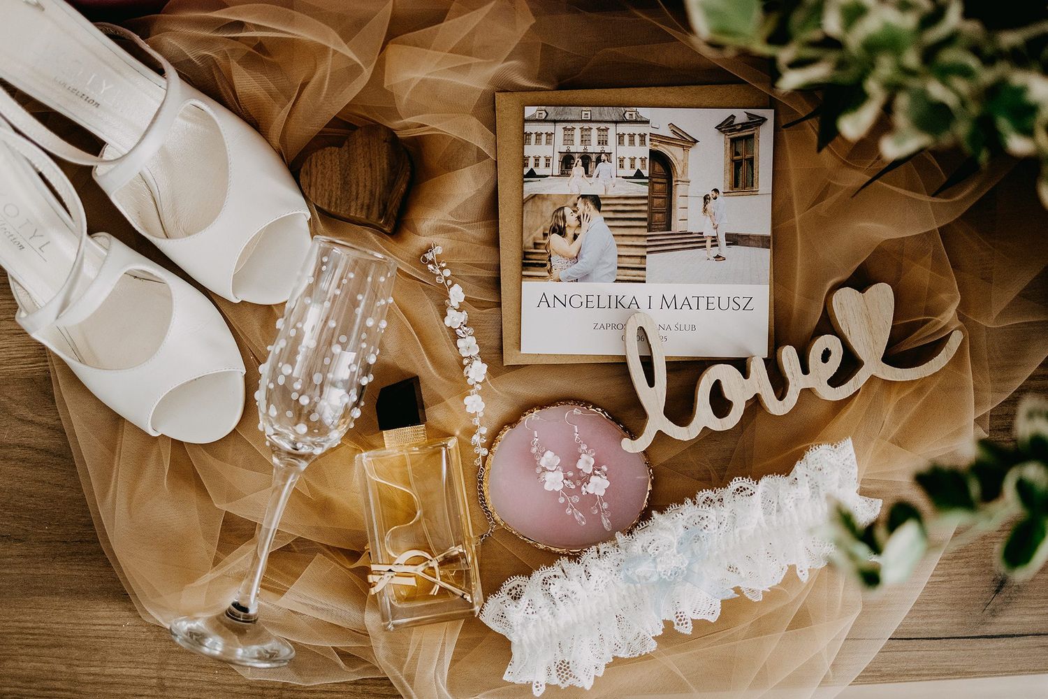 Flat lay of wedding details including shoes, champagne flutes, garter, and personalized photo book.