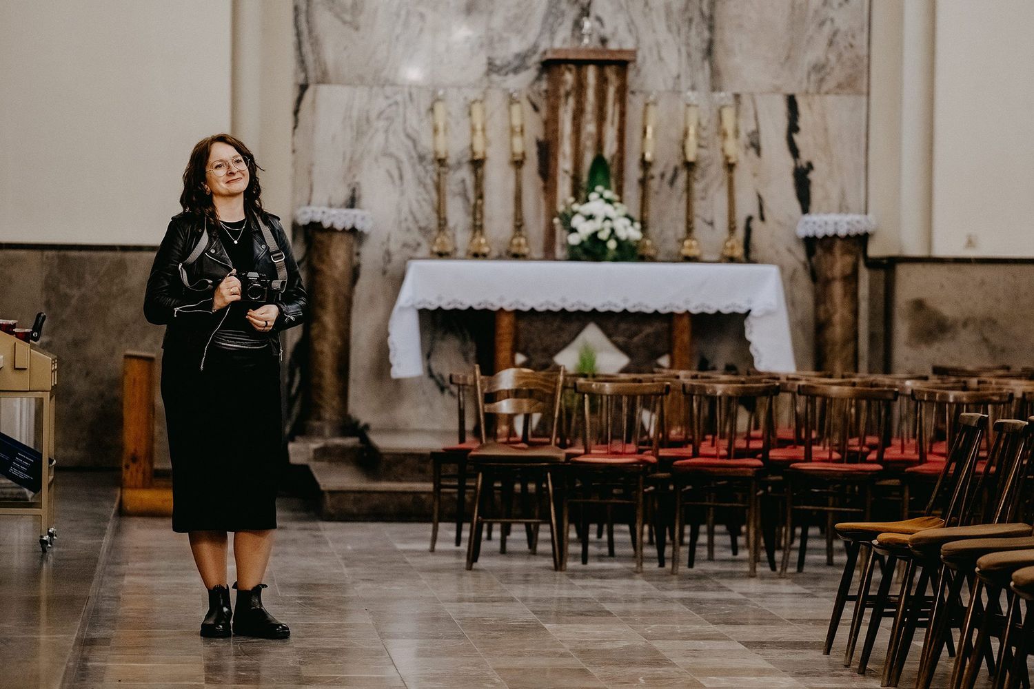Female photographer standing in ornate church interior before altar.