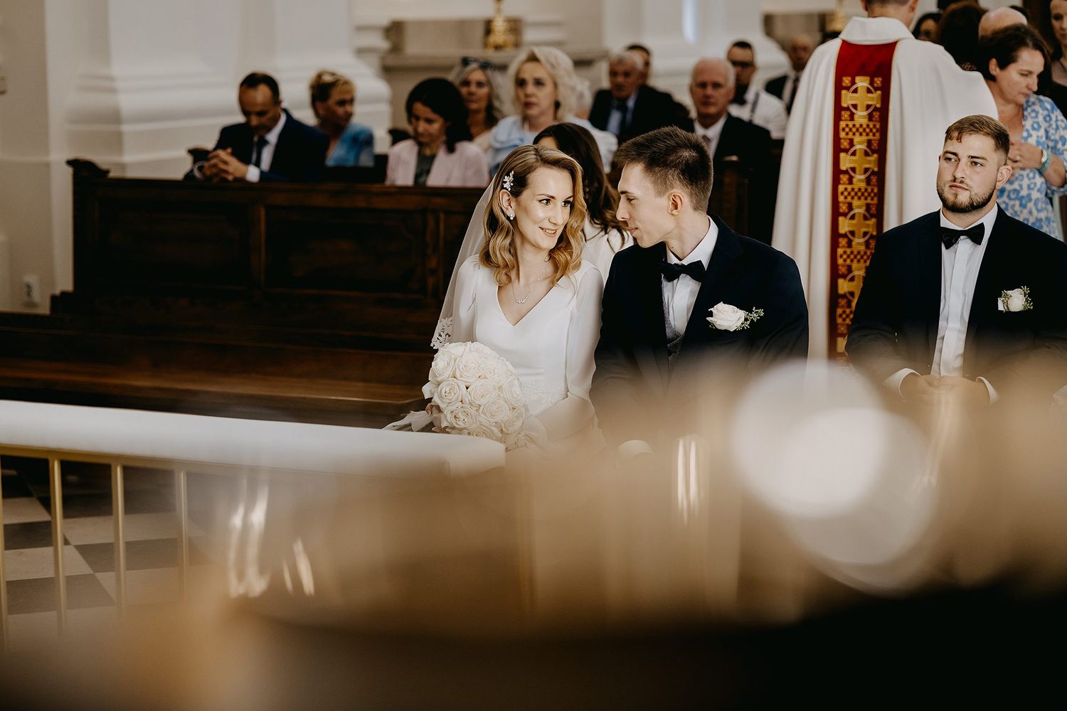 Bride and groom sharing tender moment at church altar during wedding ceremony.