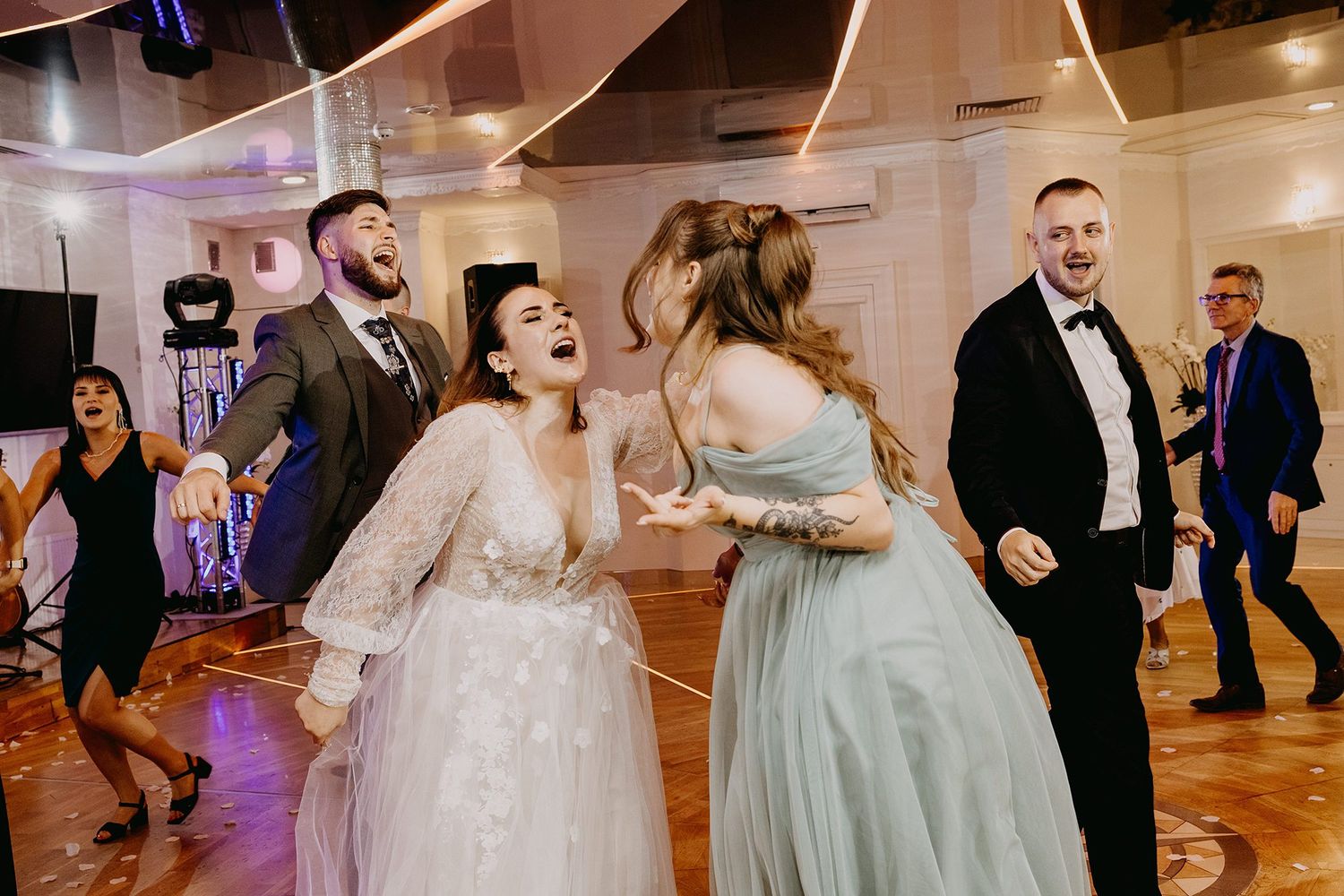 Joyful bride and wedding guests dancing and laughing together on the reception dance floor.