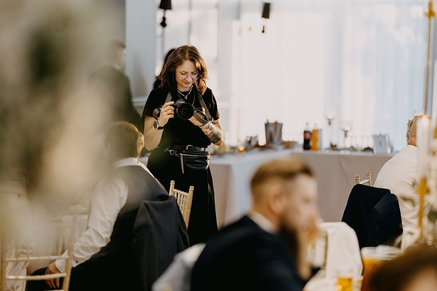 Female photographer working at elegant indoor wedding reception dinner.