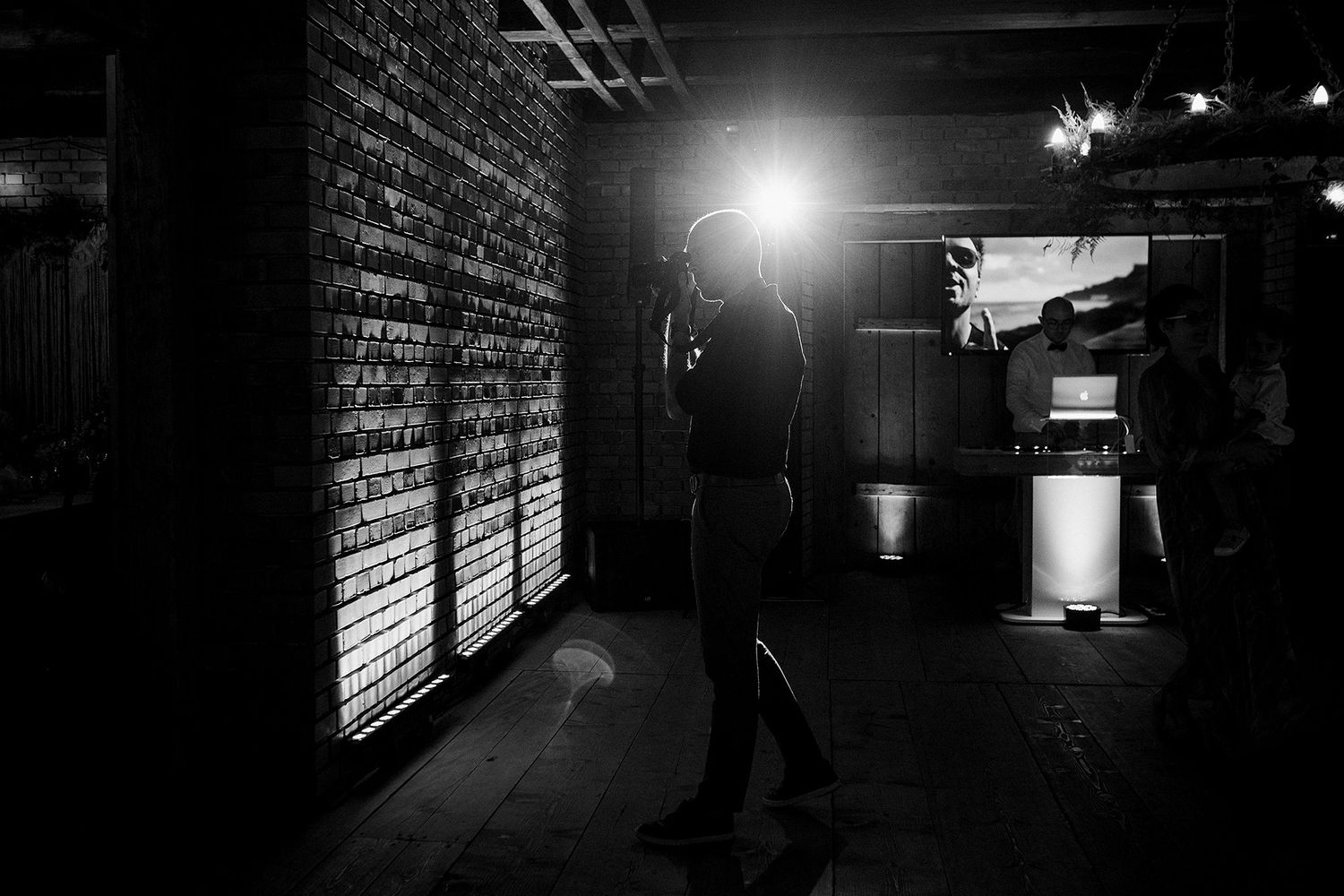 Black and white silhouette of person standing in dark venue with bright backlight.