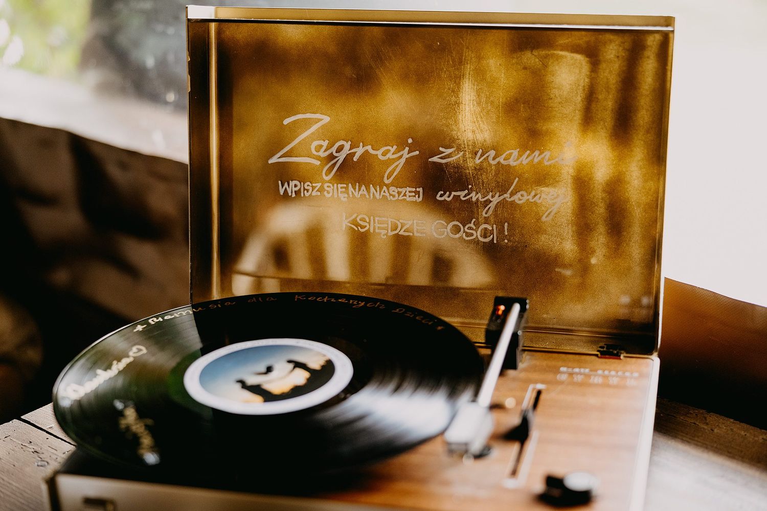 Vintage vinyl record player with golden wedding sign reading Zagraj z nami at reception.