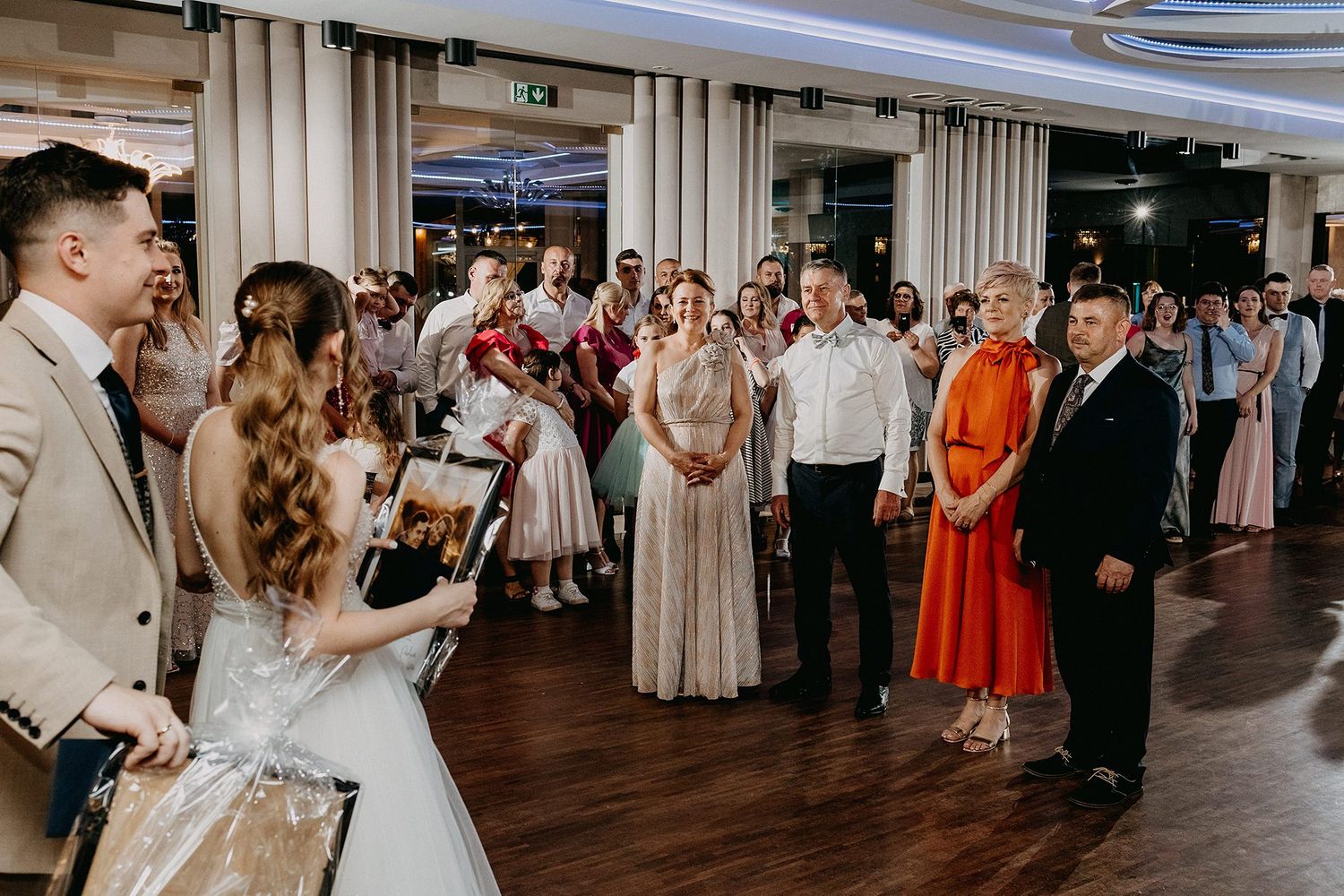 Bride and groom presenting gifts to wedding guests on a decorated reception dance floor.