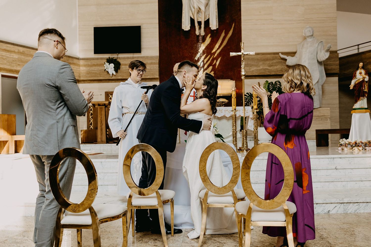 Bride and groom sharing a kiss at the altar during an elegant church ceremony.