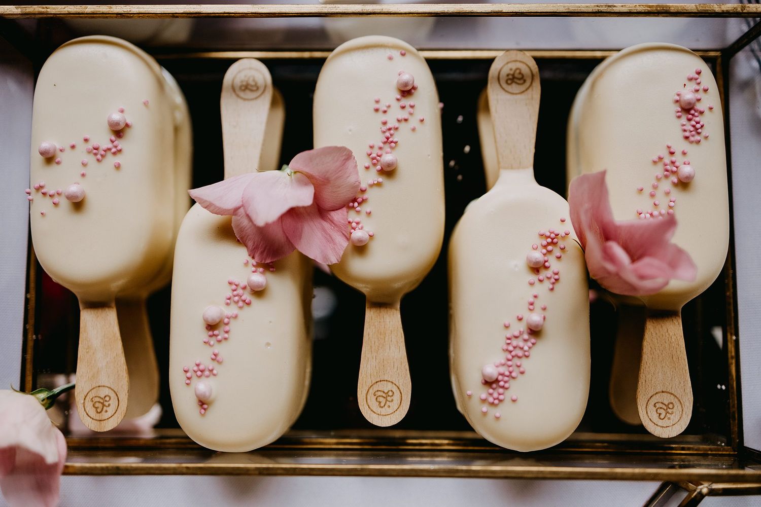 White chocolate-covered cake pops decorated with pink flowers and sprinkles.