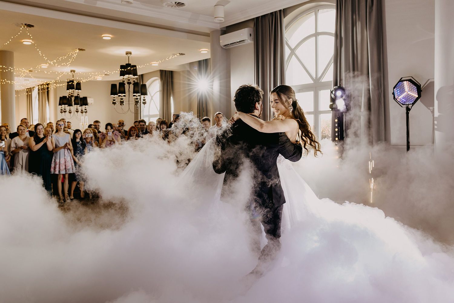 Bride and groom share romantic first dance surrounded by dramatic fog machine effects on dance floor.