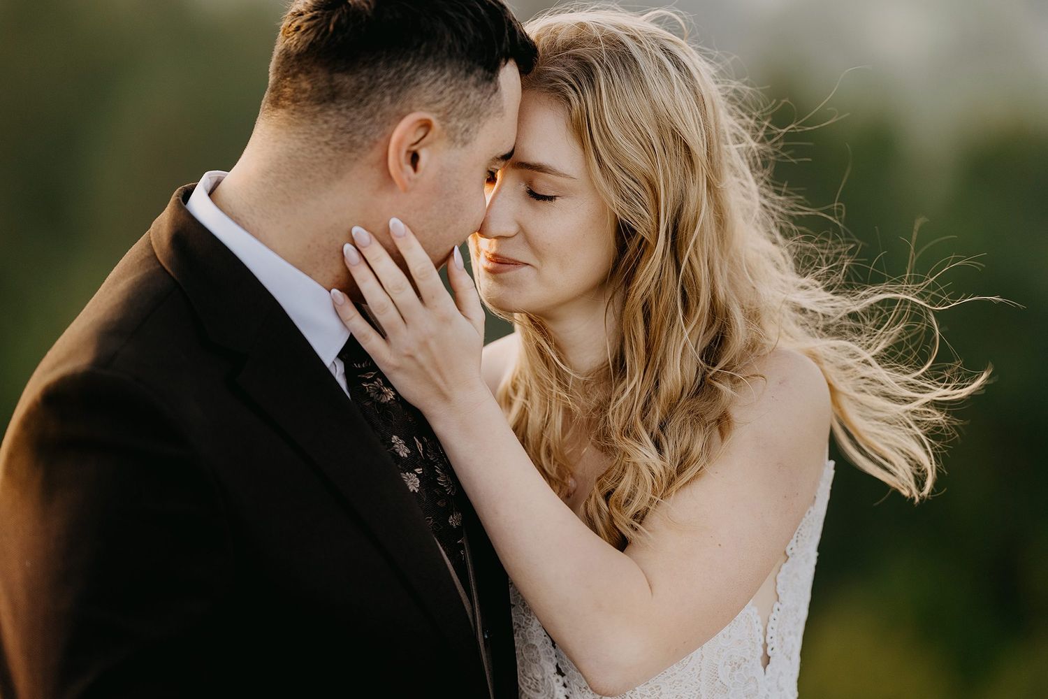 Bride tenderly touching grooms face in an intimate close-up wedding portrait at sunset.