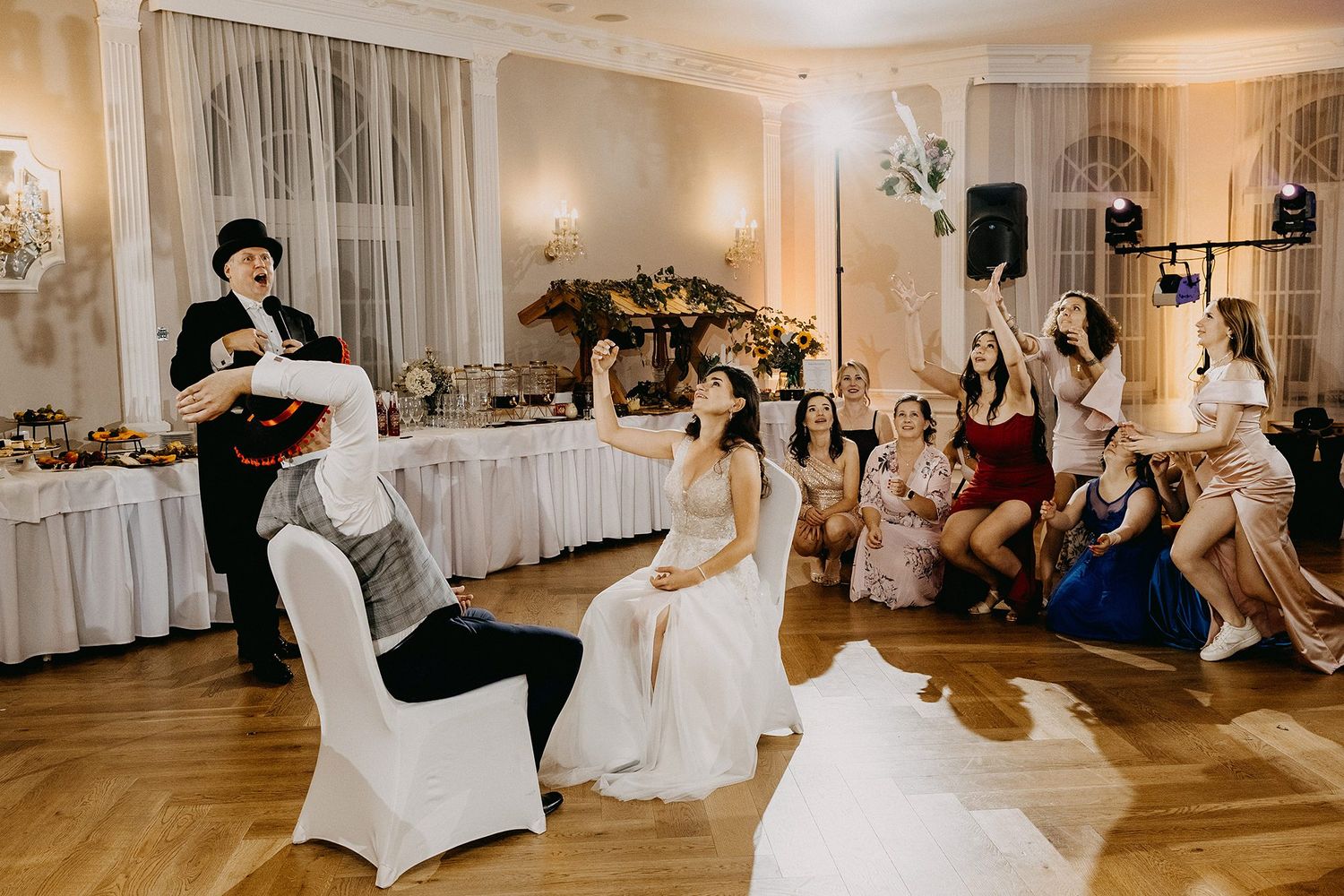 Magician performing at a wedding reception with bride seated and guests cheering in an elegant ballroom.