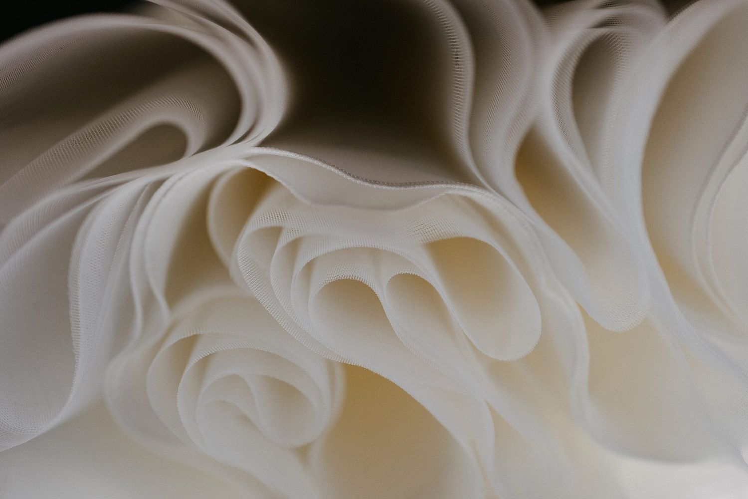 Close-up of elegant white ruffled wedding cake layers with soft cream fondant details.
