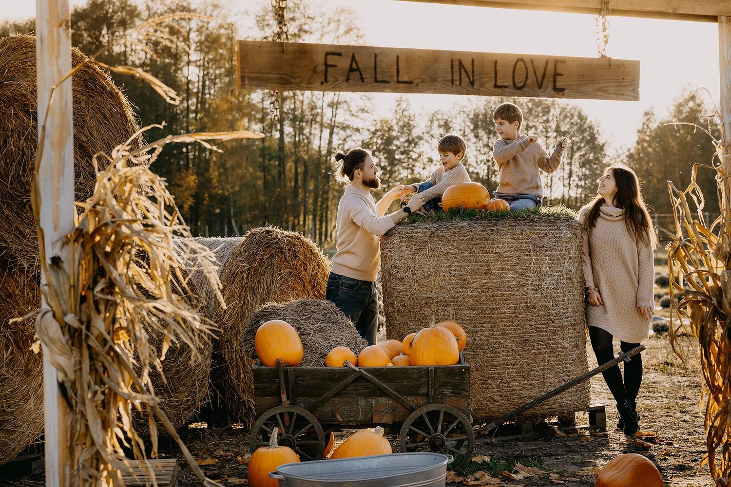 Family enjoying fall harvest festival with pumpkins and hay bales.