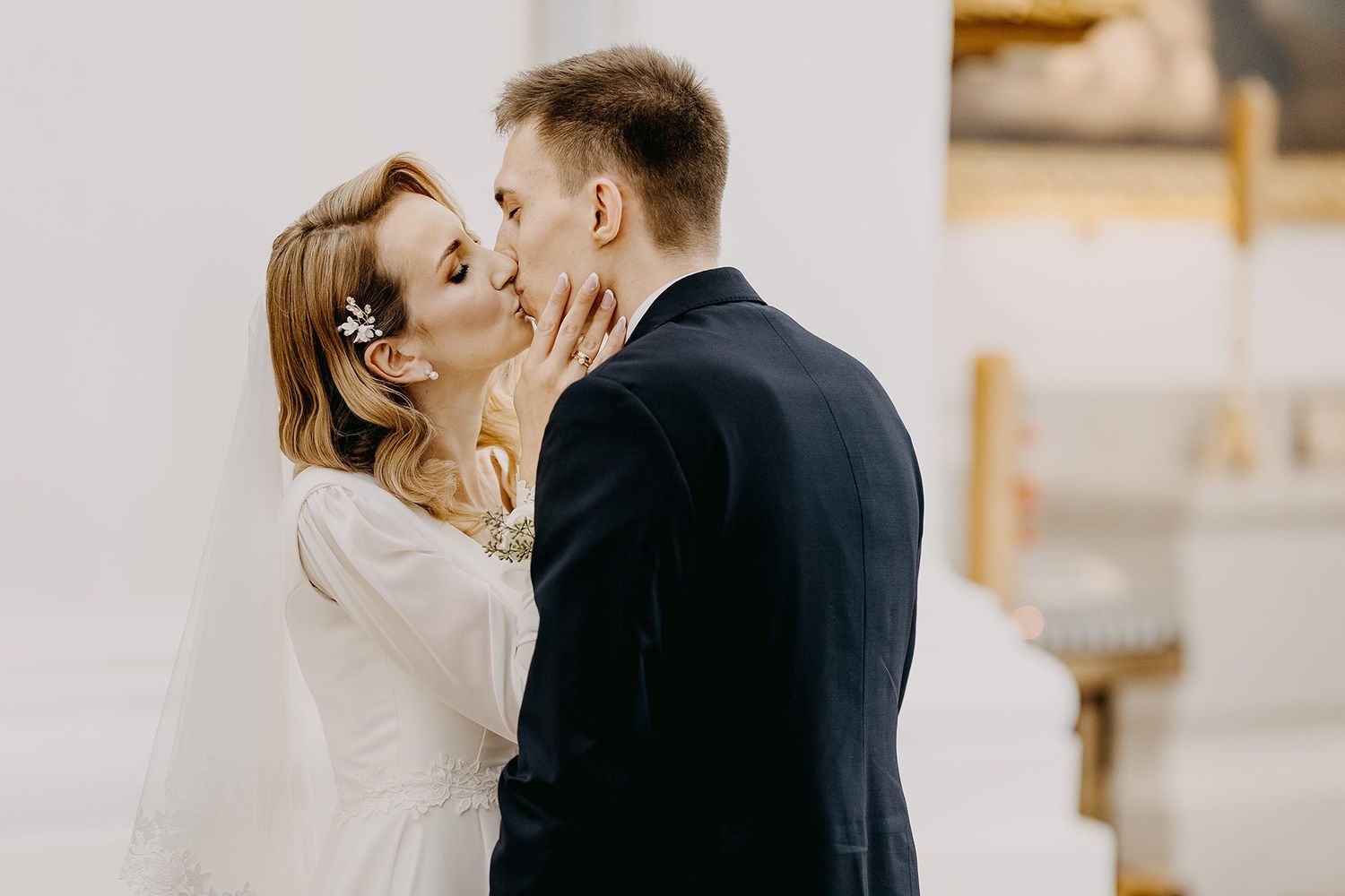 A bride and groom share a tender first kiss at the altar during their elegant wedding ceremony.