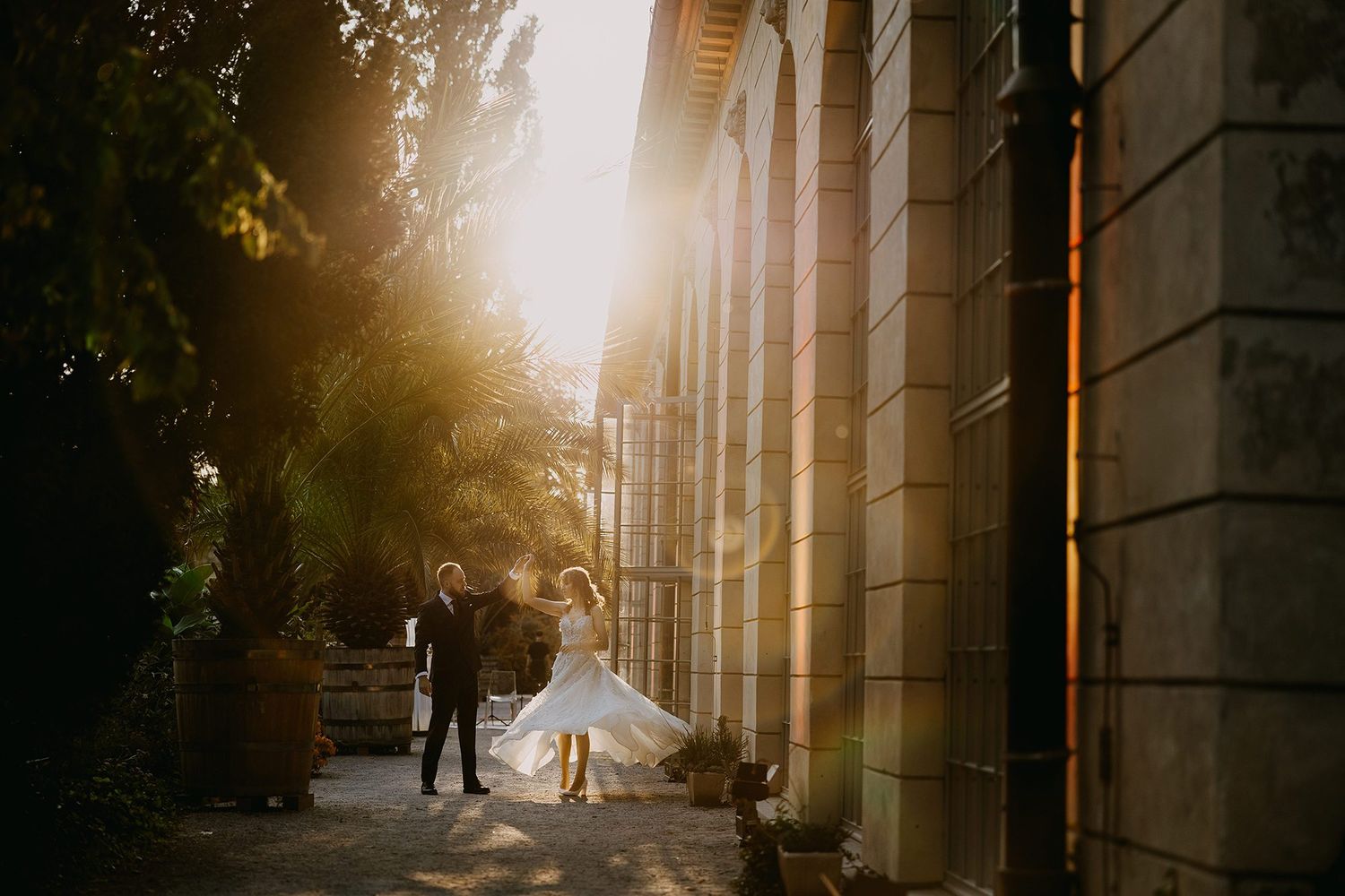Couple sharing a romantic moment in golden sunset light beside a grand historic building.