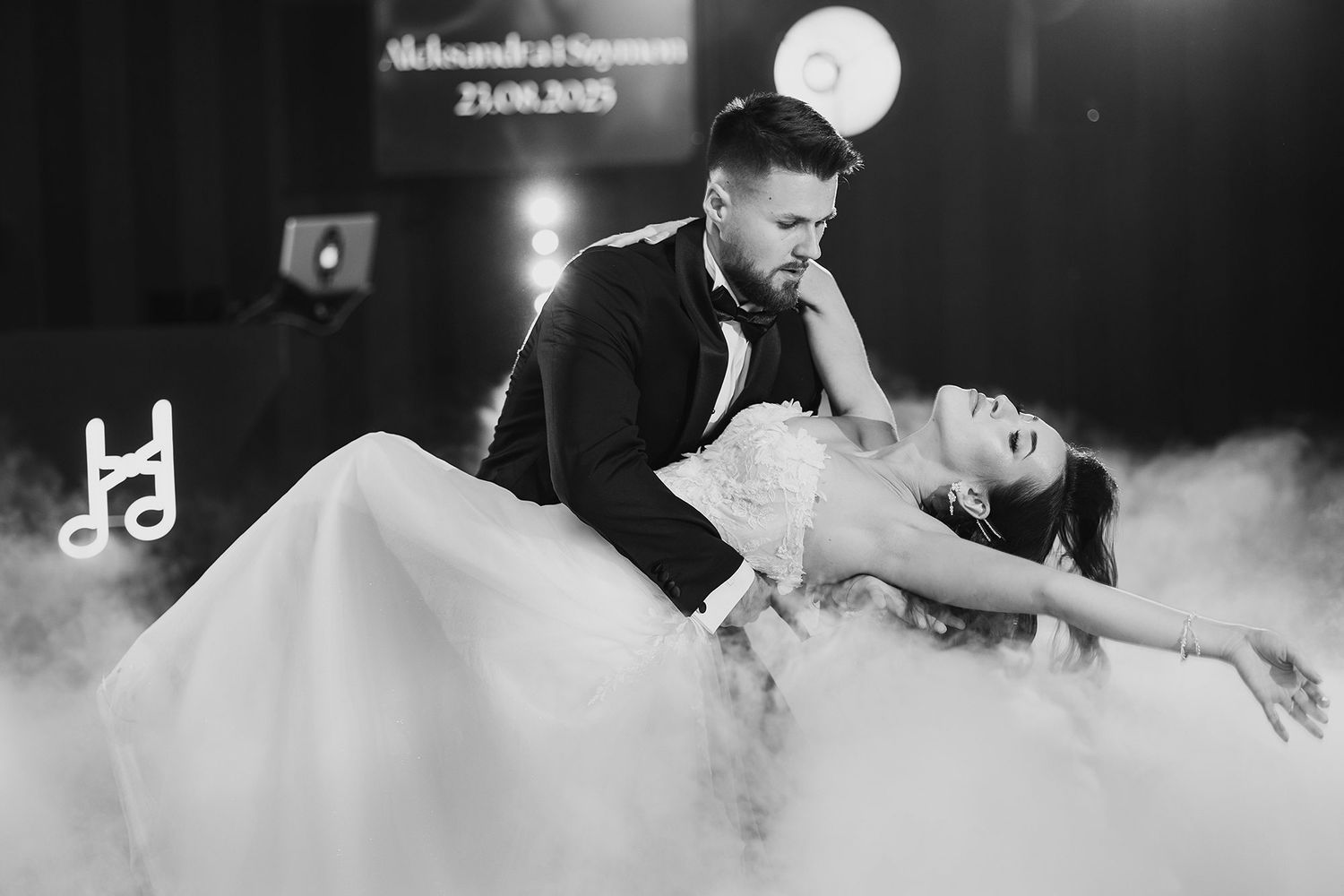 Black and white romantic dip pose of bride and groom during their first dance in fog.