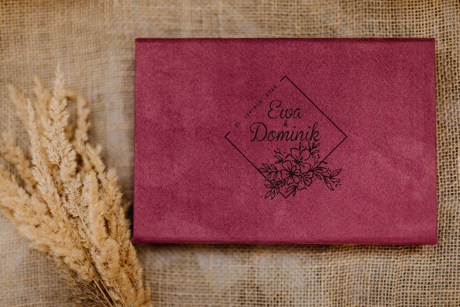 Burgundy velvet wedding keepsake box with embossed floral design reading Ewa i Dominik on burlap.