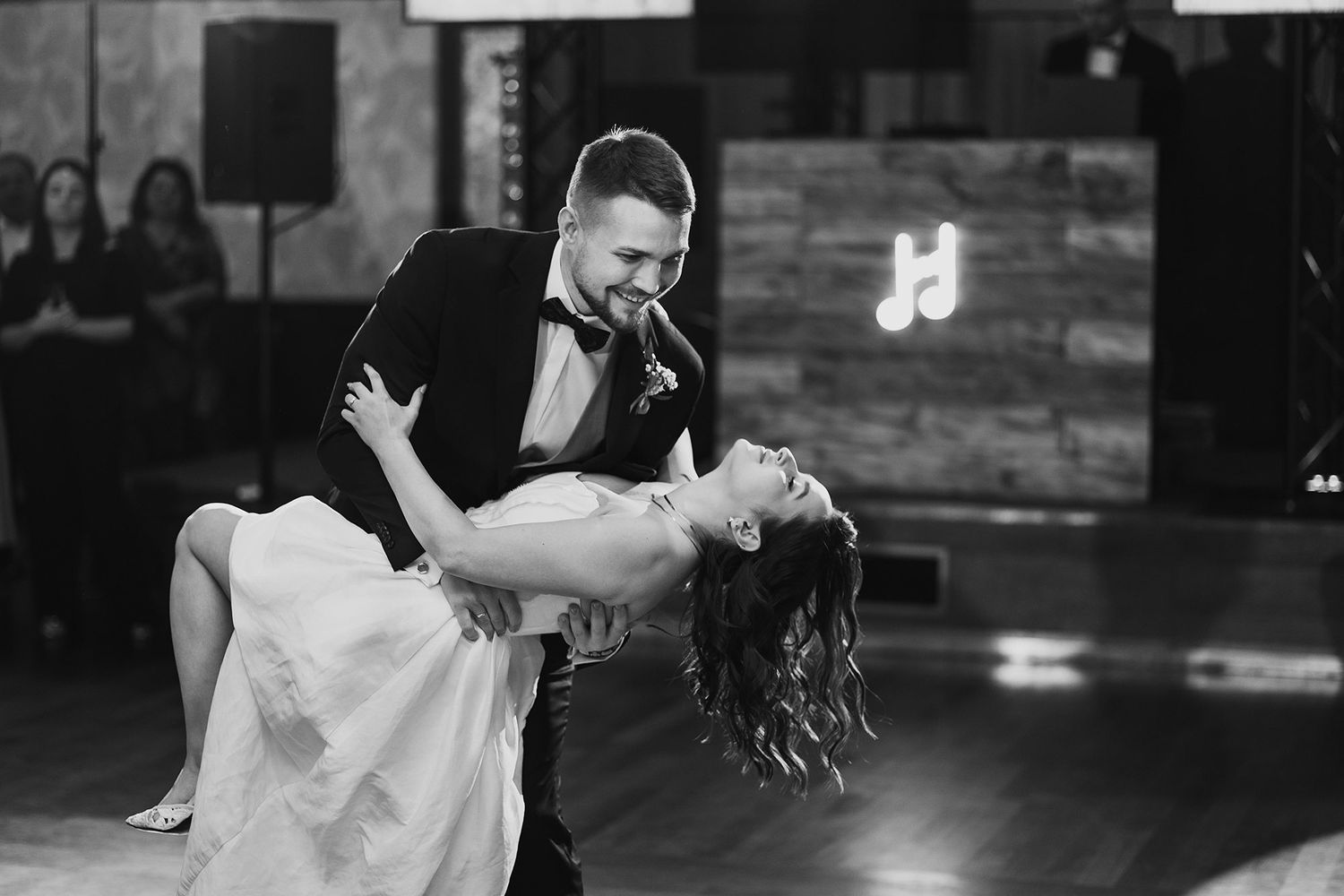 Bride and groom sharing a dramatic dip during their first dance in black and white.
