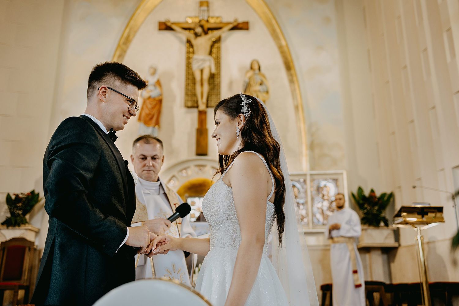 Bride and groom exchanging vows at a church altar with a priest officiating the wedding ceremony.