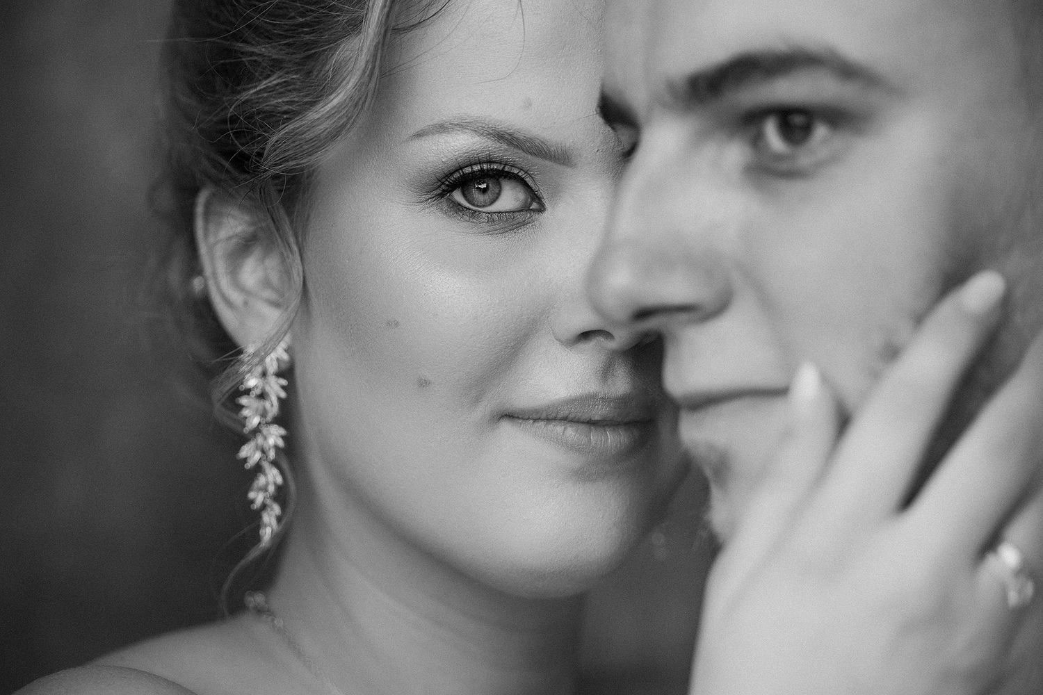 Intimate black and white close-up portrait of a bride and groom with elegant pearl earrings.