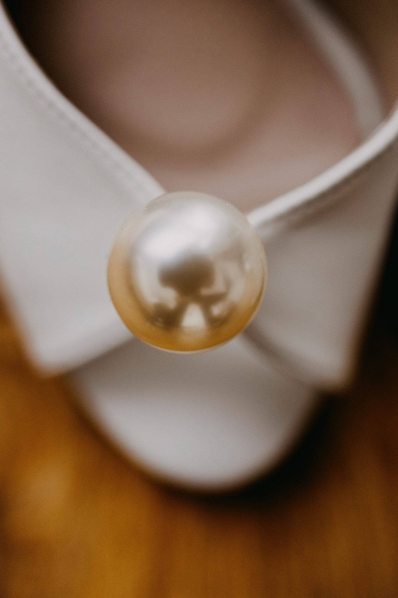 Close-up of white bridal shoe with elegant pearl bow detail.