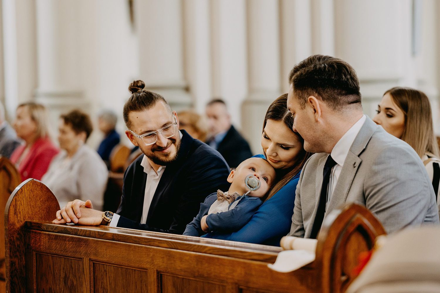 Family members share a joyful moment together in church pew during baptism ceremony.