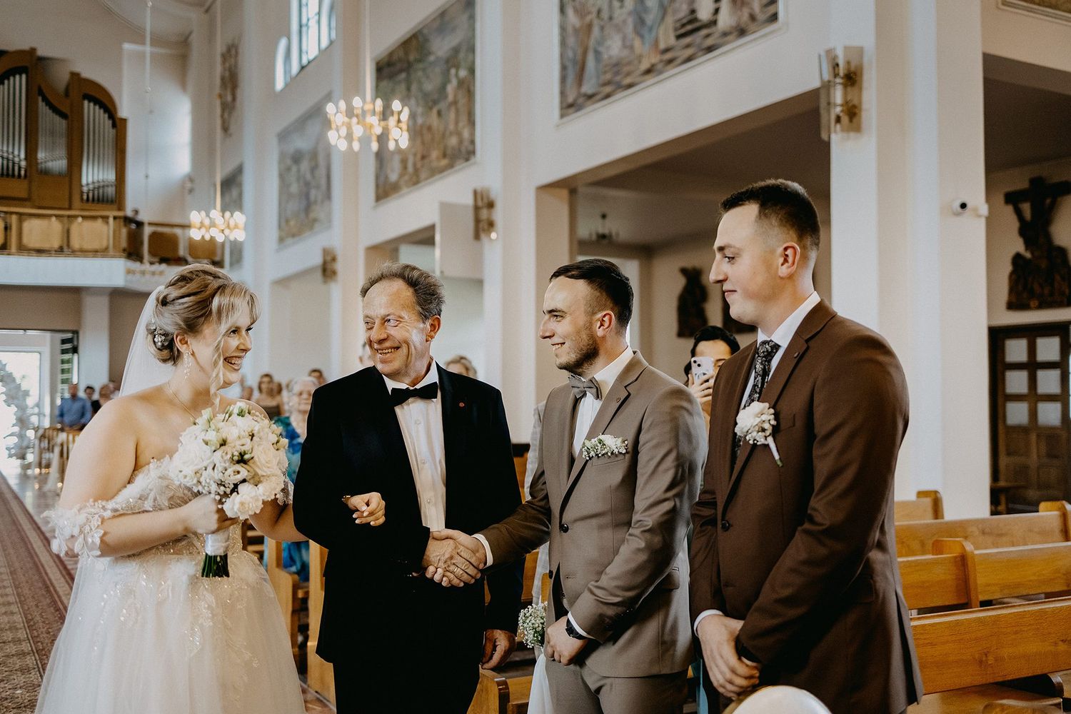 Bride and groom sharing a joyful moment with guests inside an elegant church during a wedding ceremony.