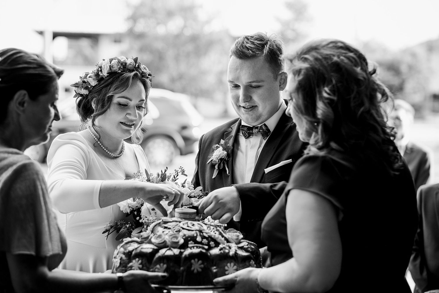 Black and white photo of bride and groom receiving traditional bread welcome ceremony from guests.