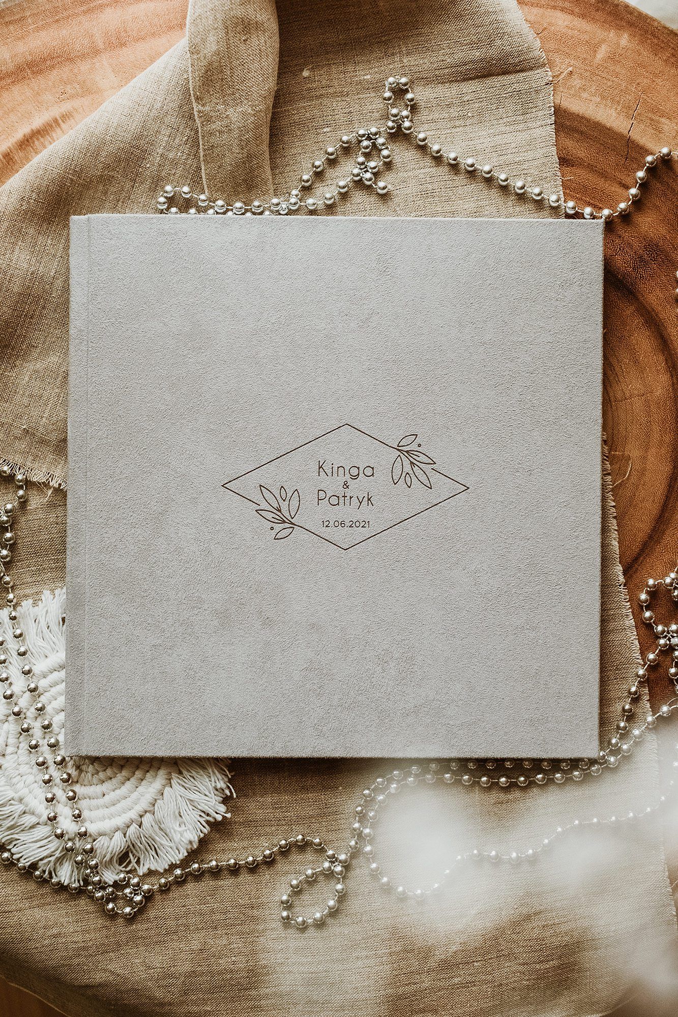 Gray wedding photo album cover with botanical diamond frame design featuring names Kinga and Patryk dated 12.09.2021.