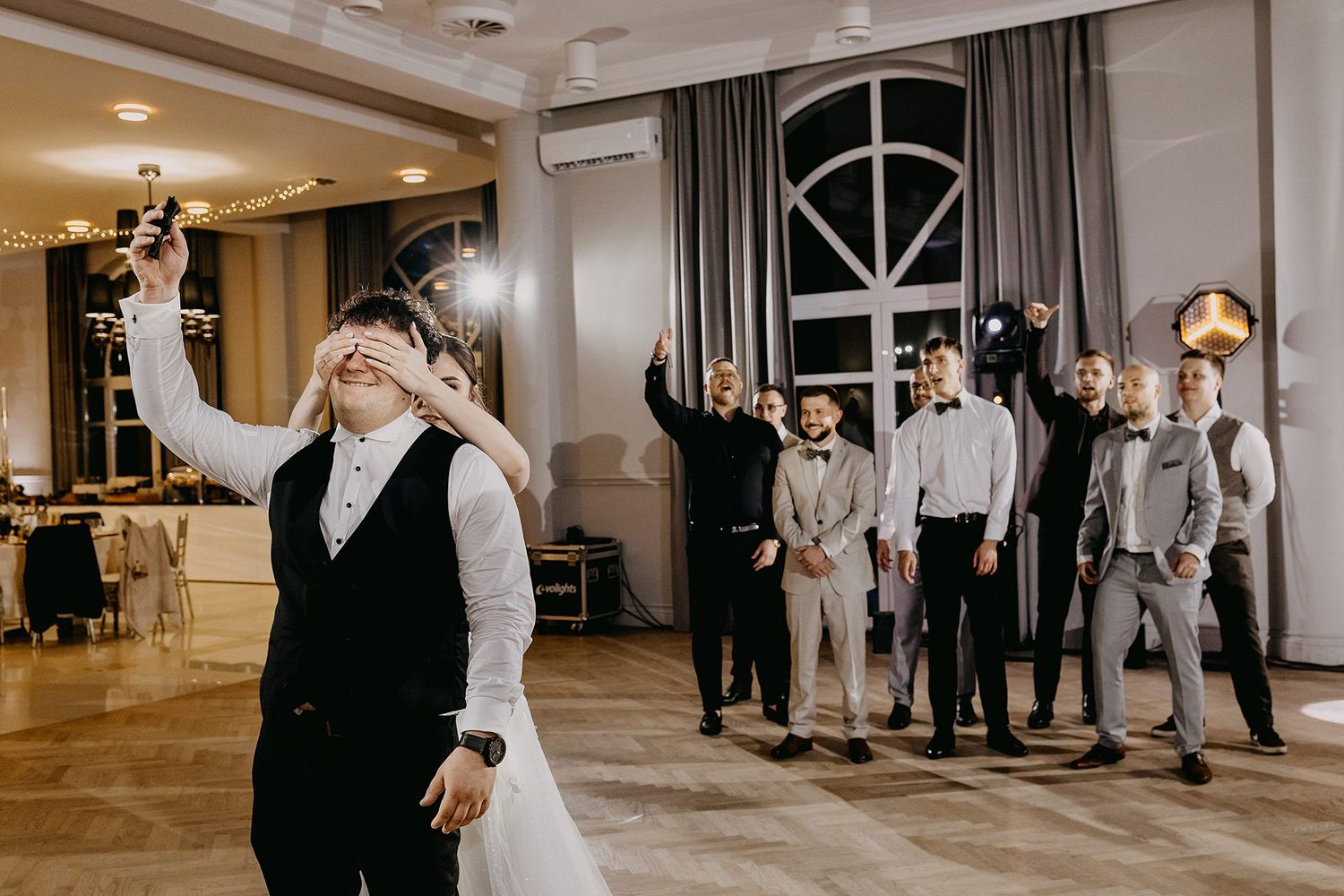 Groom tosses garter to groomsmen during lively wedding reception celebration.