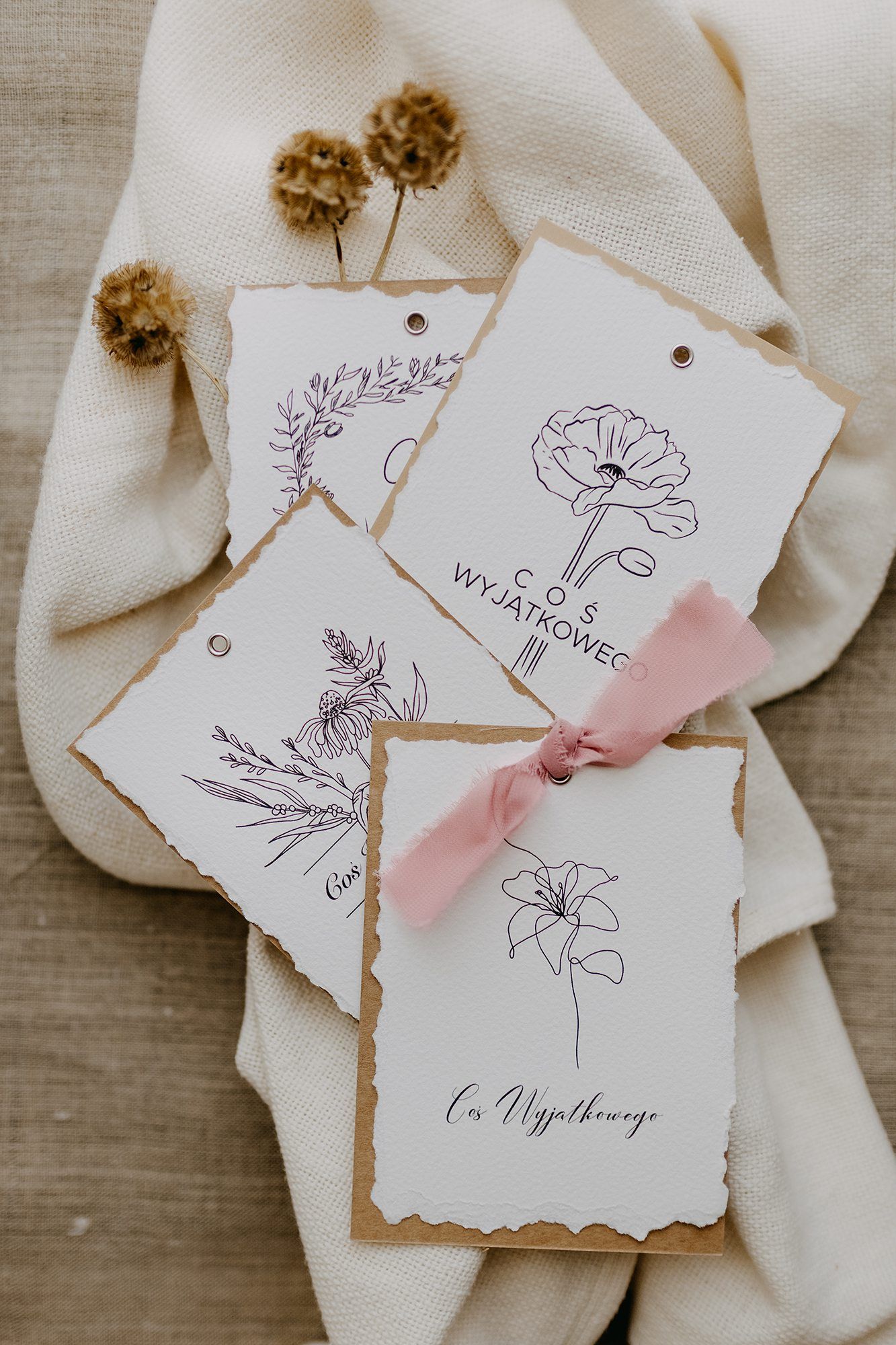 Collection of botanical line art gift cards with floral designs and pink ribbon on linen cloth.