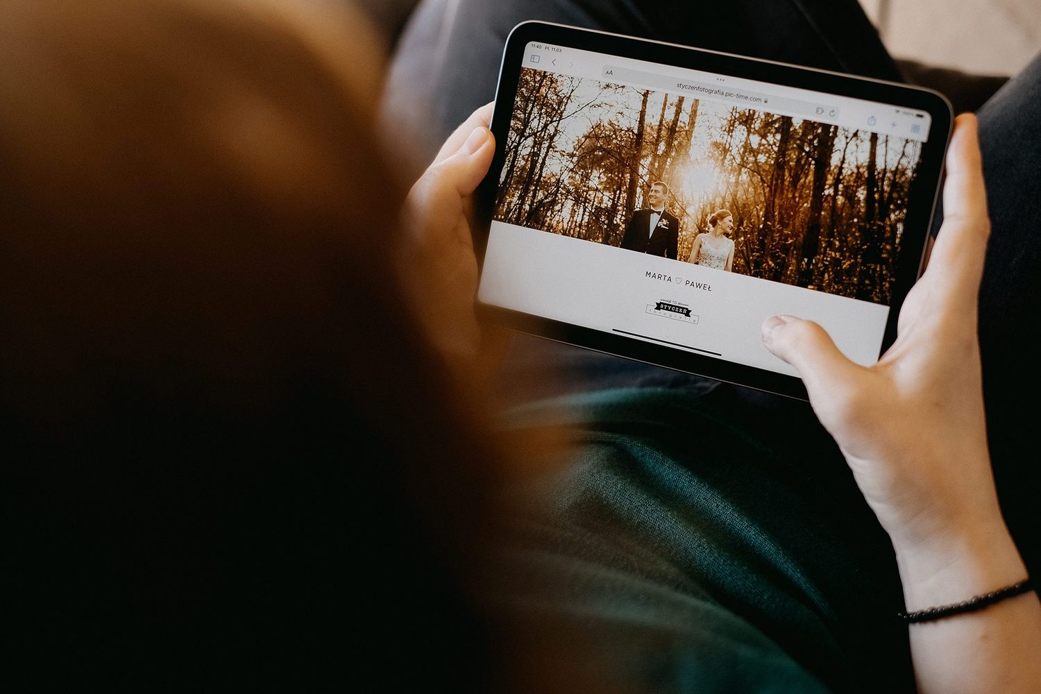 Person viewing a wedding photography website with golden forest image on a tablet.