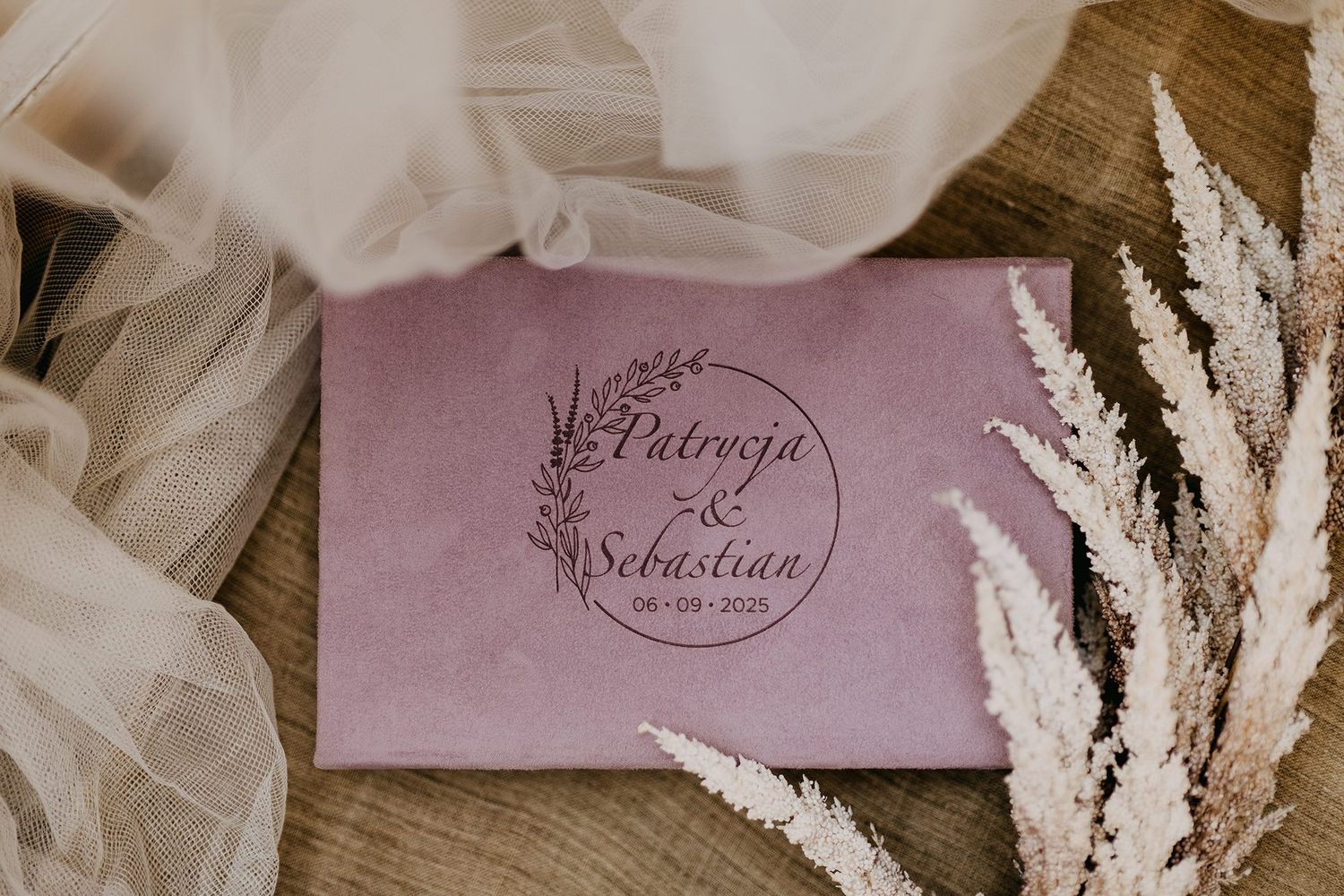 Dusty pink velvet wedding album engraved with Patrycja and Sebastian names and floral design.